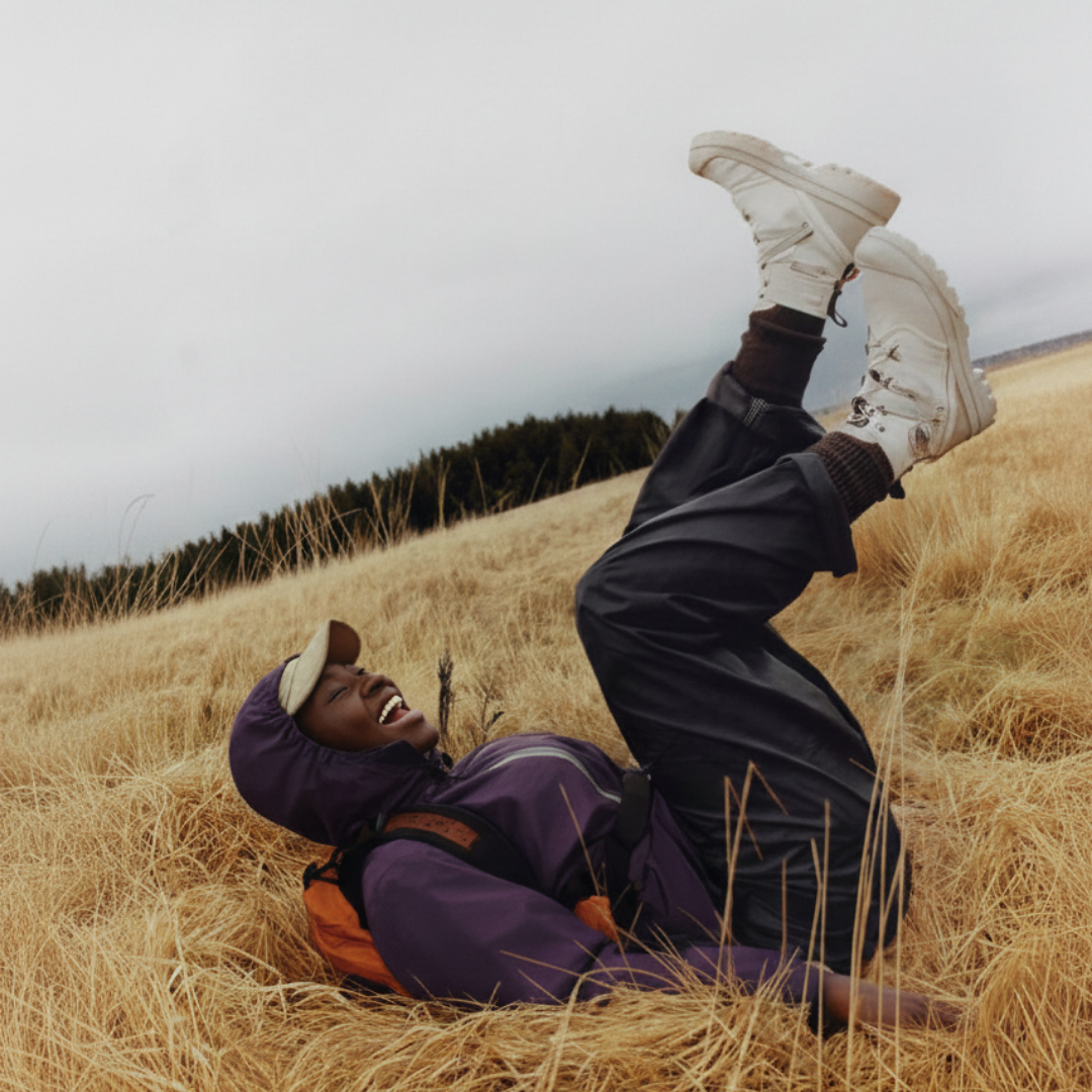 Persona riendo en un campo, disfrutando del momento en plena naturaleza, símbolo de una vida nómada y consciente